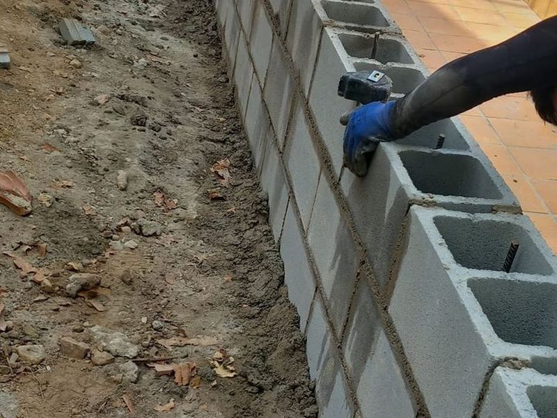 Albañil levantando un muro de bloques de hormigón recibidos con mortero