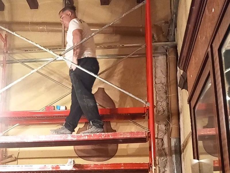 Operario trabajando sobre un andamio interior en el techo de vigas de una vivienda antigua
